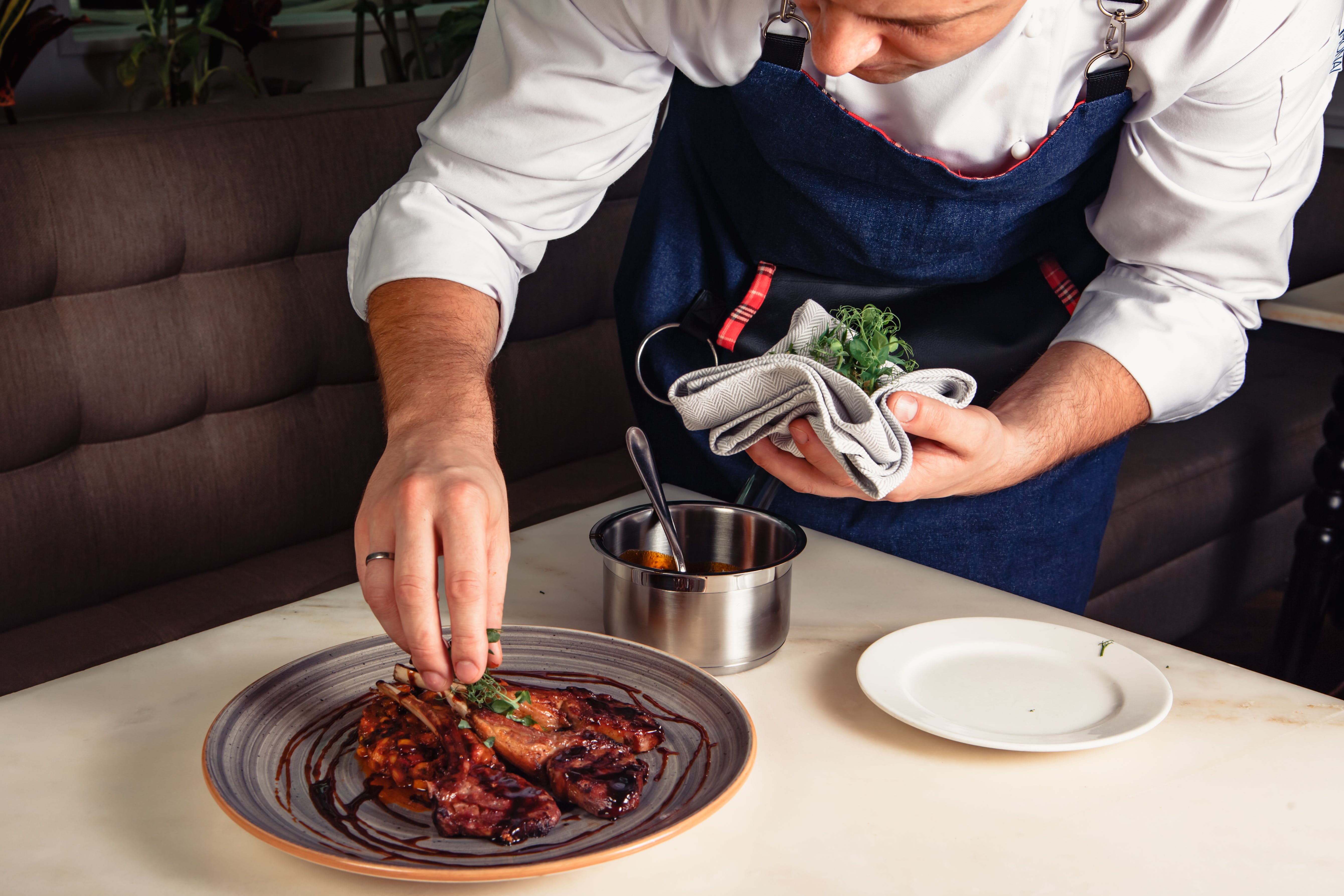 A cook arranges a plate nicely on a table